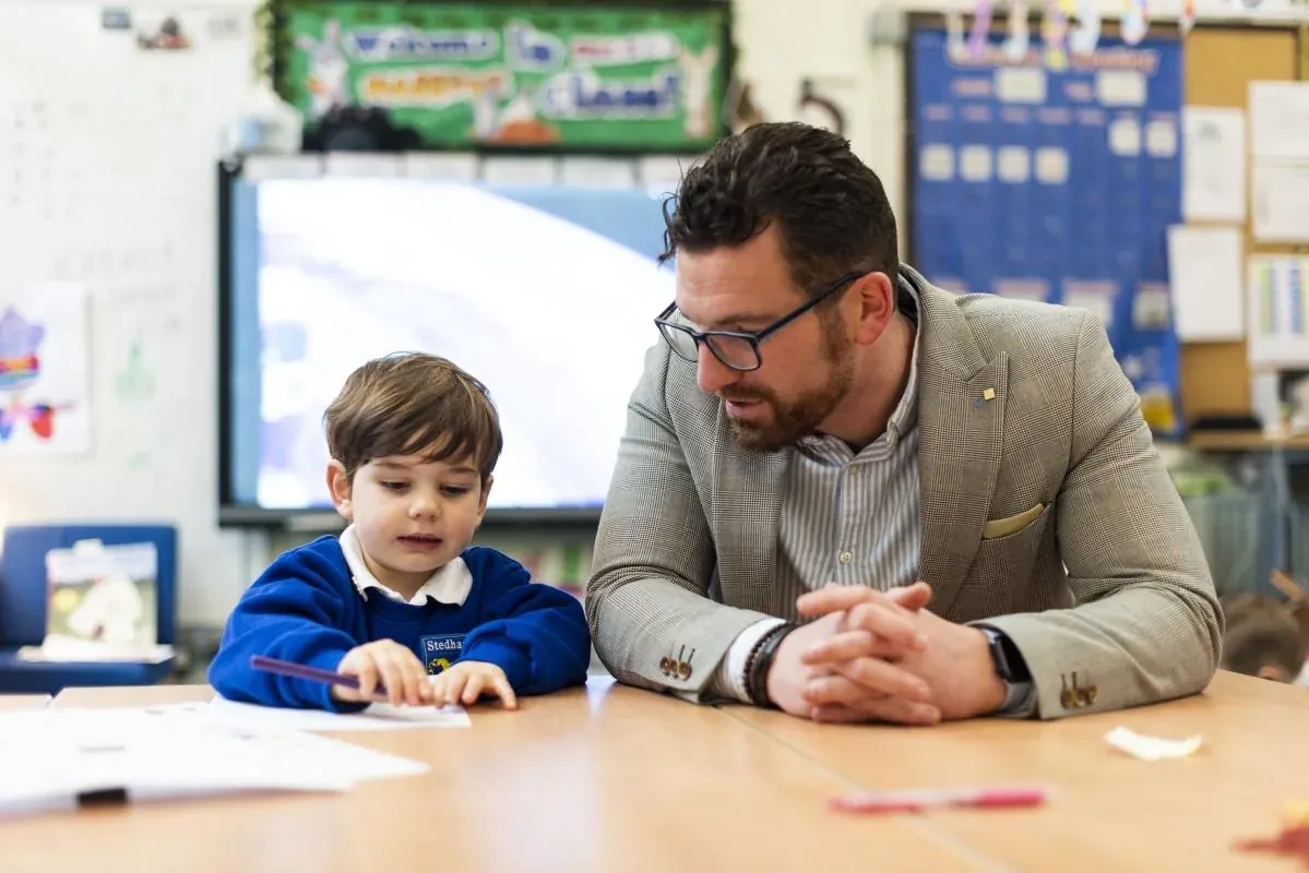 A teacher and a pupil working together at a classroom table
