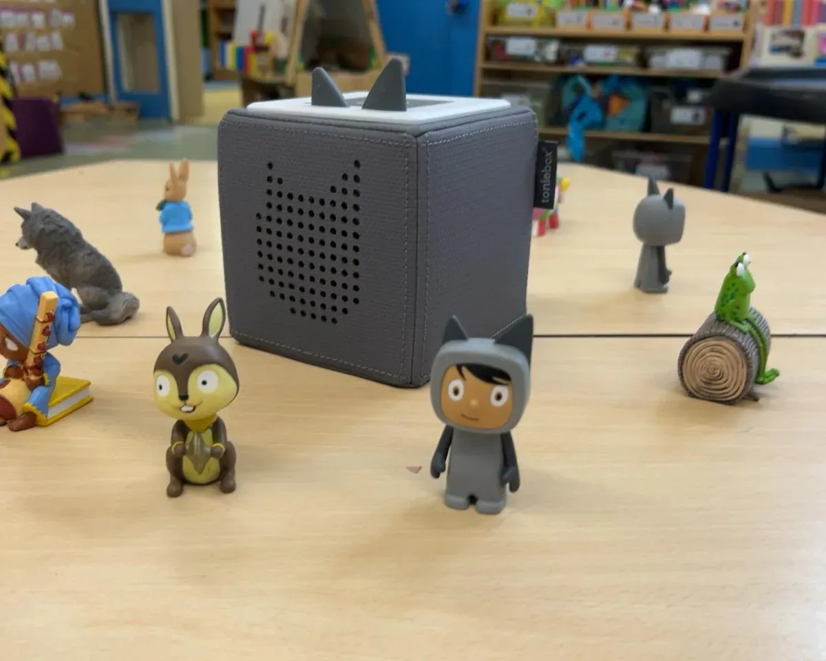 A Tonies audio box surrounded by story character figures in the reading corner
